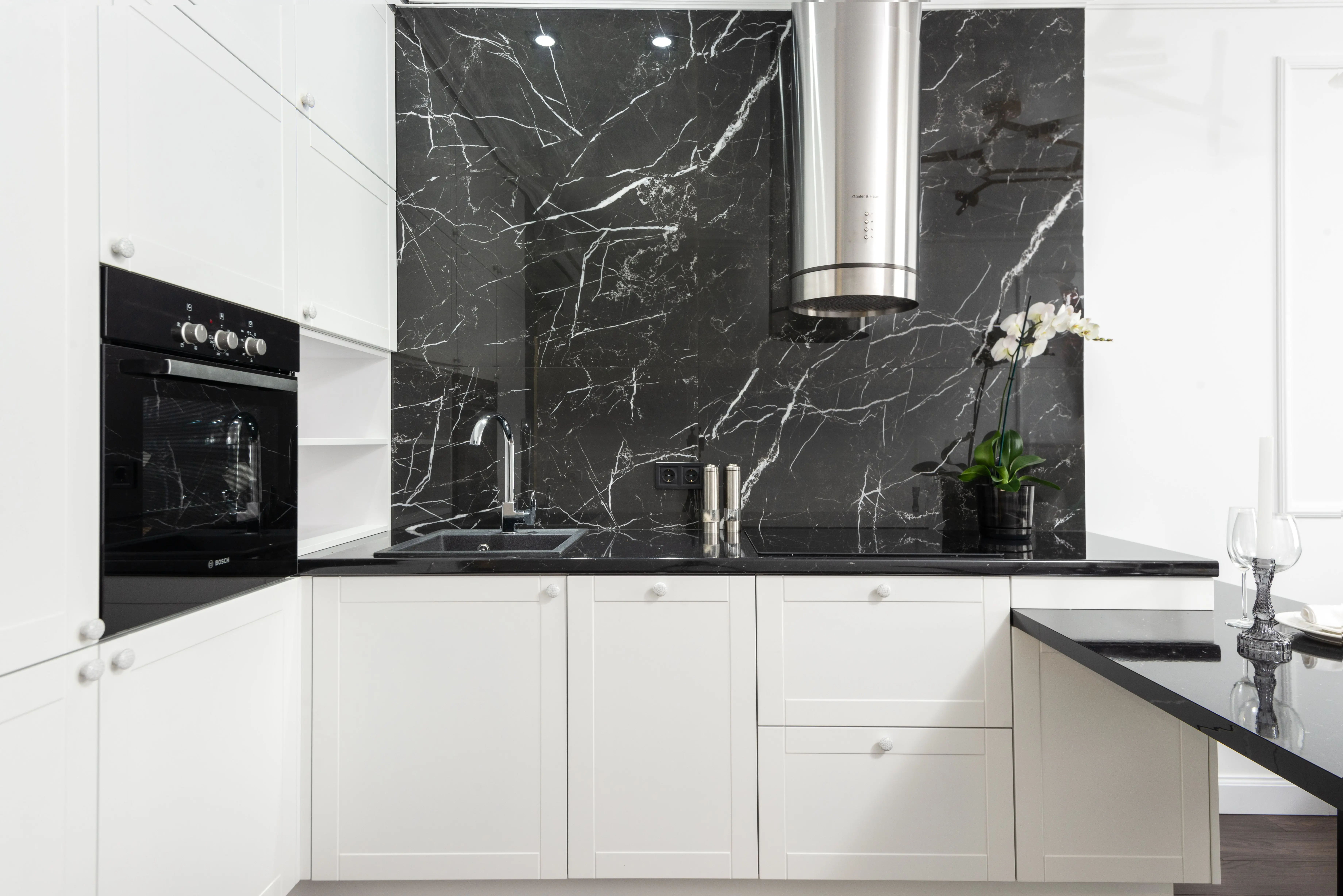 black subway tile Sleek contemporary kitchen featuring white cabinets and black marble backsplash for a clean, minimalistic design.