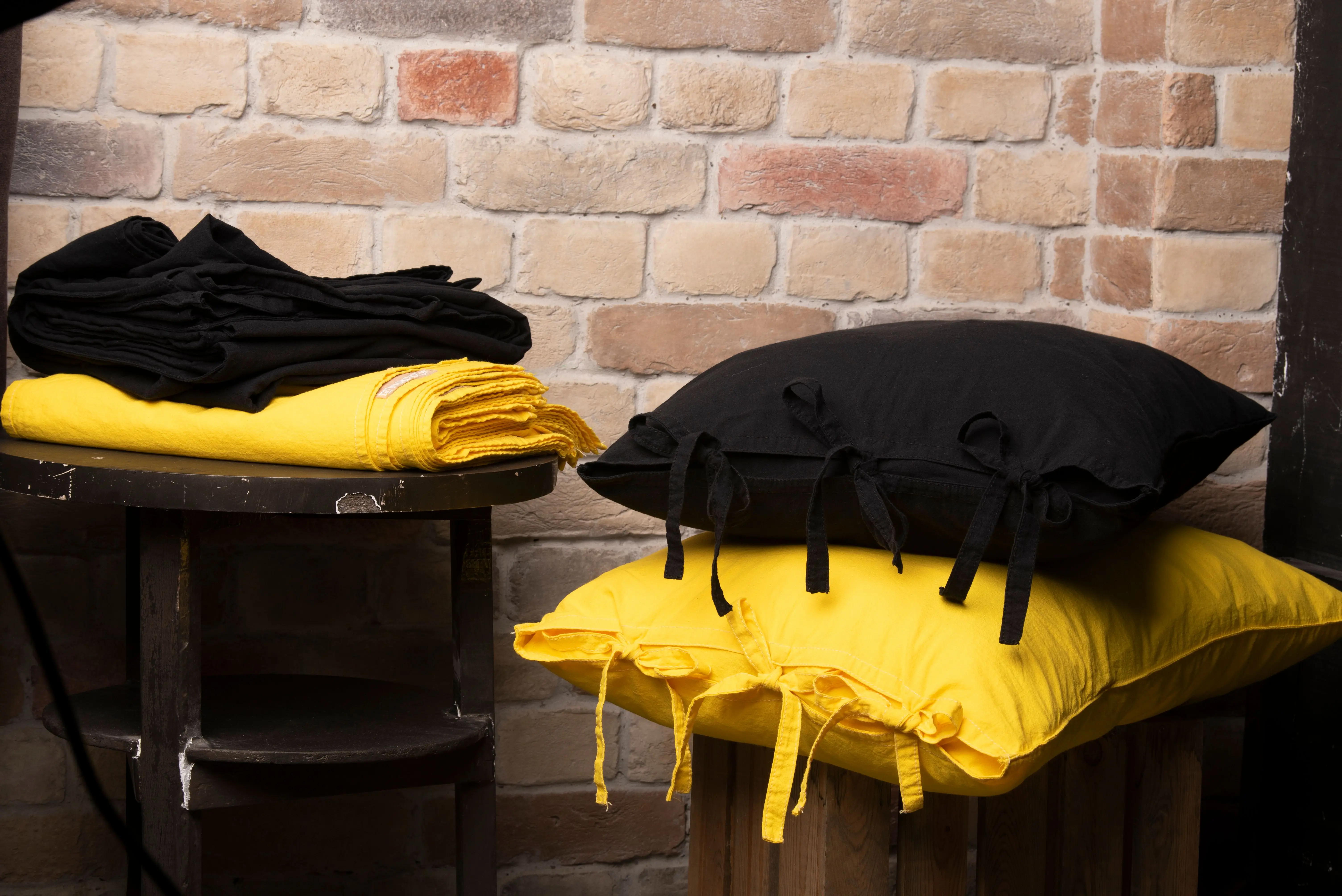 blue throw pillow Colorful black and yellow pillows with towels against a brick wall, creating a cozy, rustic vibe.