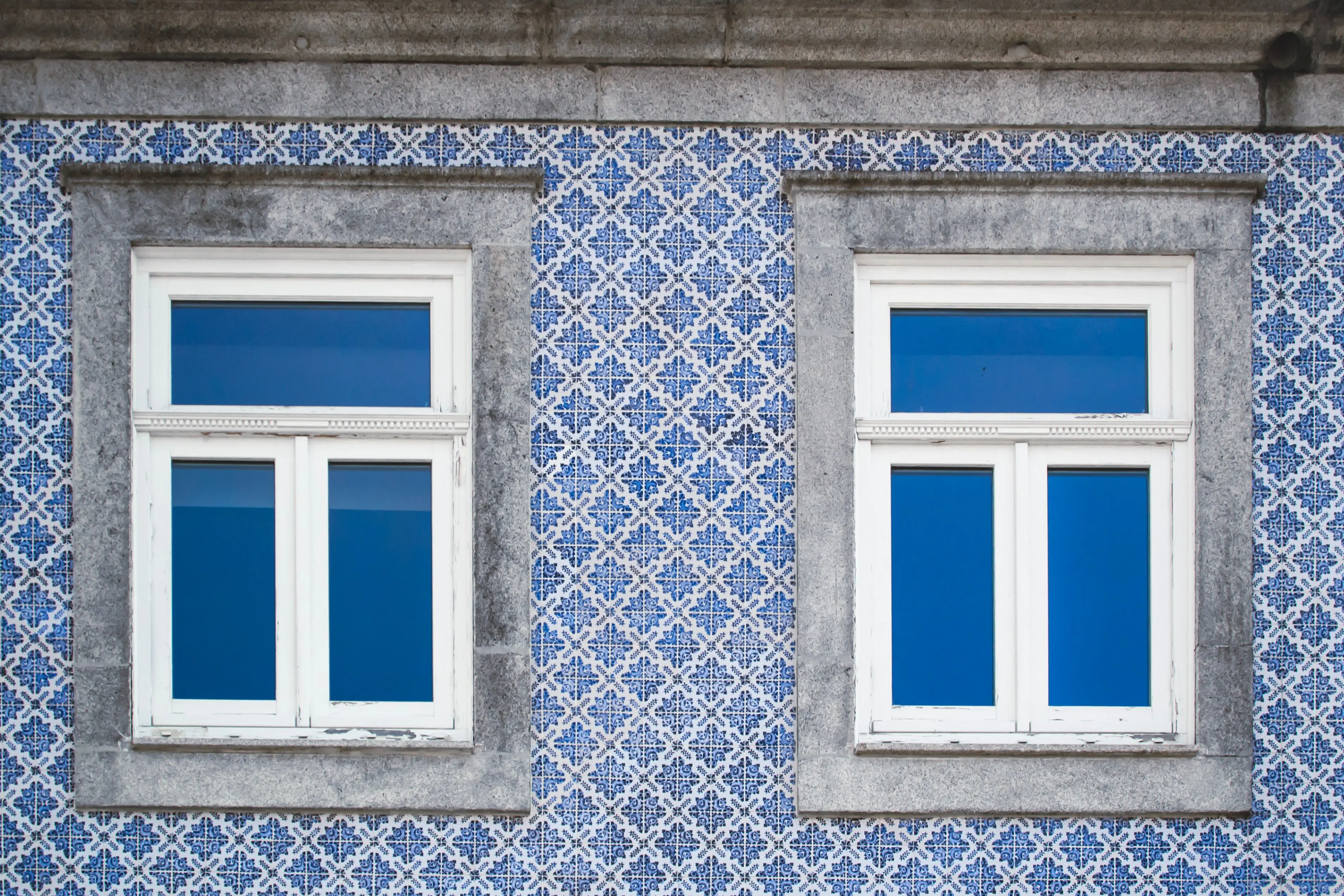 blue subway tile Close-up of a traditional Portuguese facade in Oporto featuring blue decorative tiles and white windows.