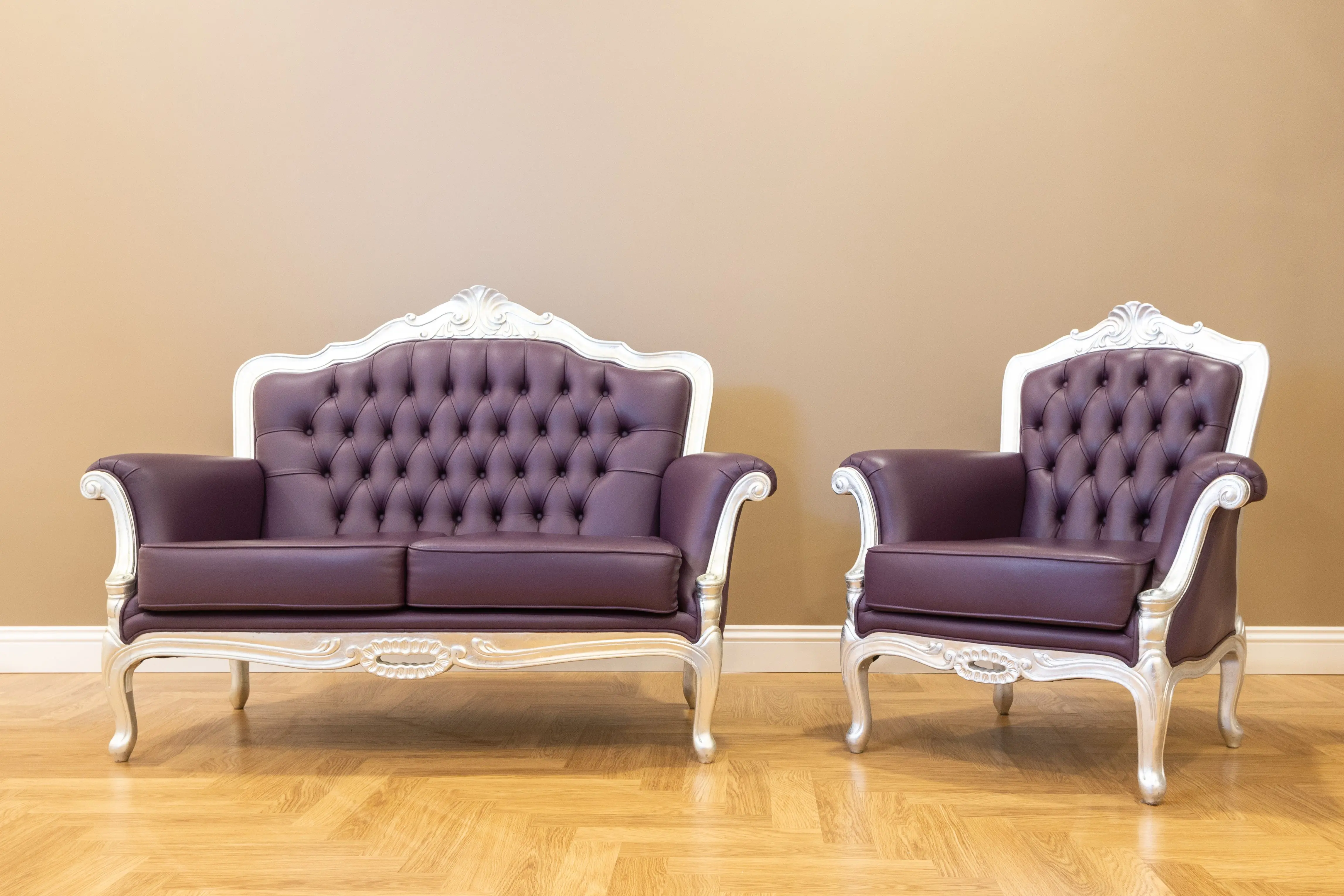 brown sectional sofa Elegant vintage-style sofa and chair with tufted leather upholstery on a wooden floor.
