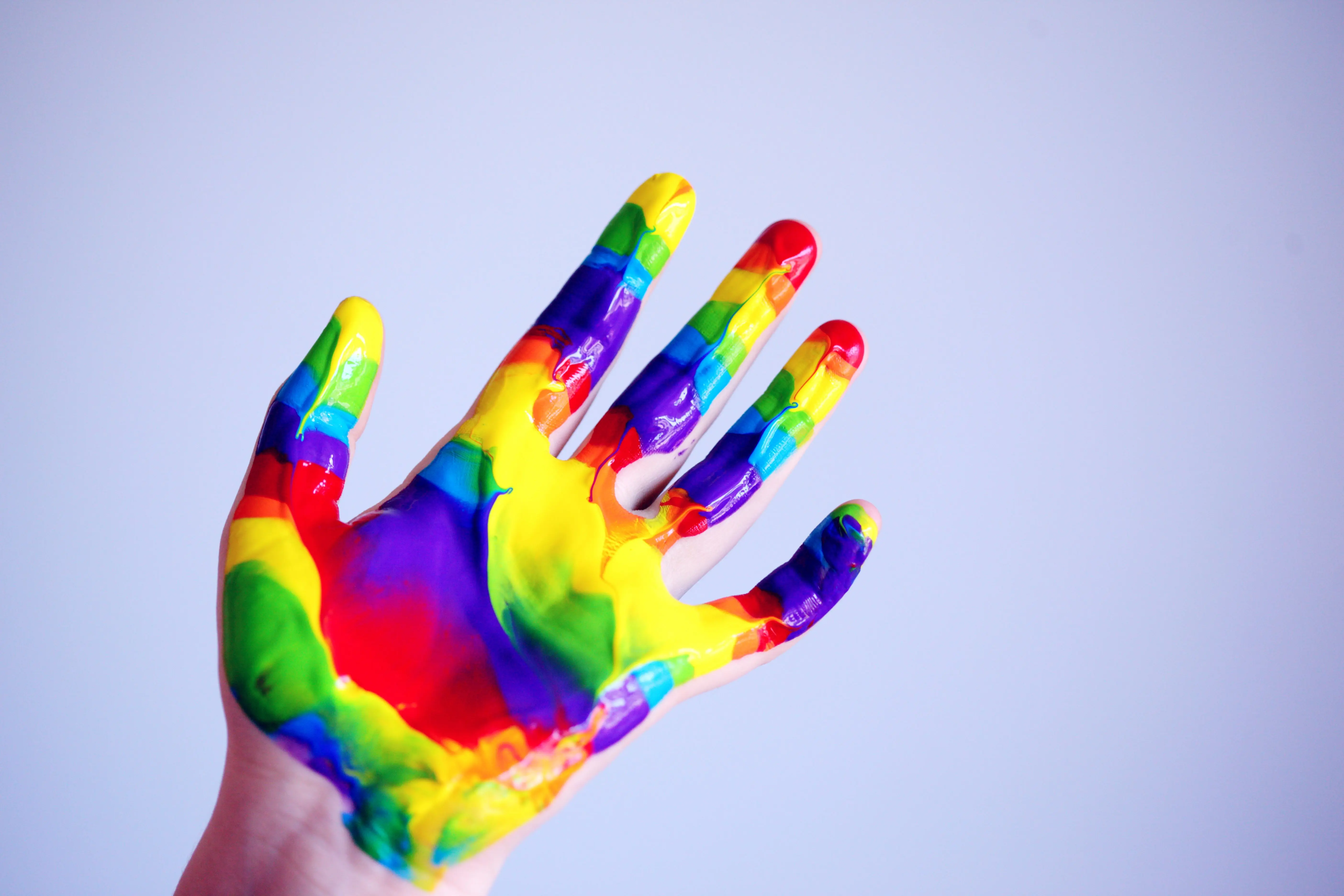 christmas handprint crafts A vibrant hand covered in rainbow paint against a plain background, symbolizing creativity.