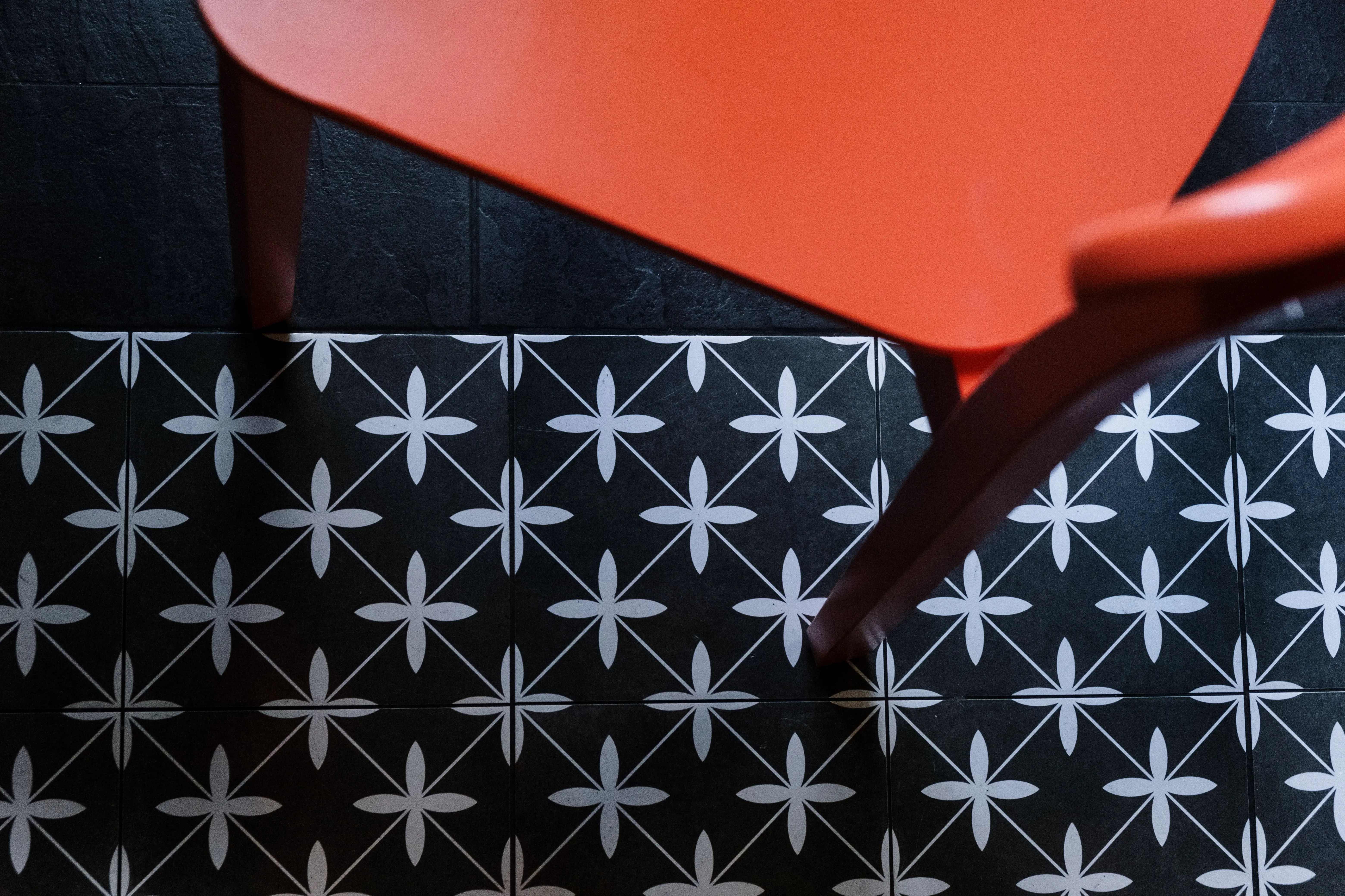black subway tile Top view of an orange chair on black and white geometric patterned floor tiles.