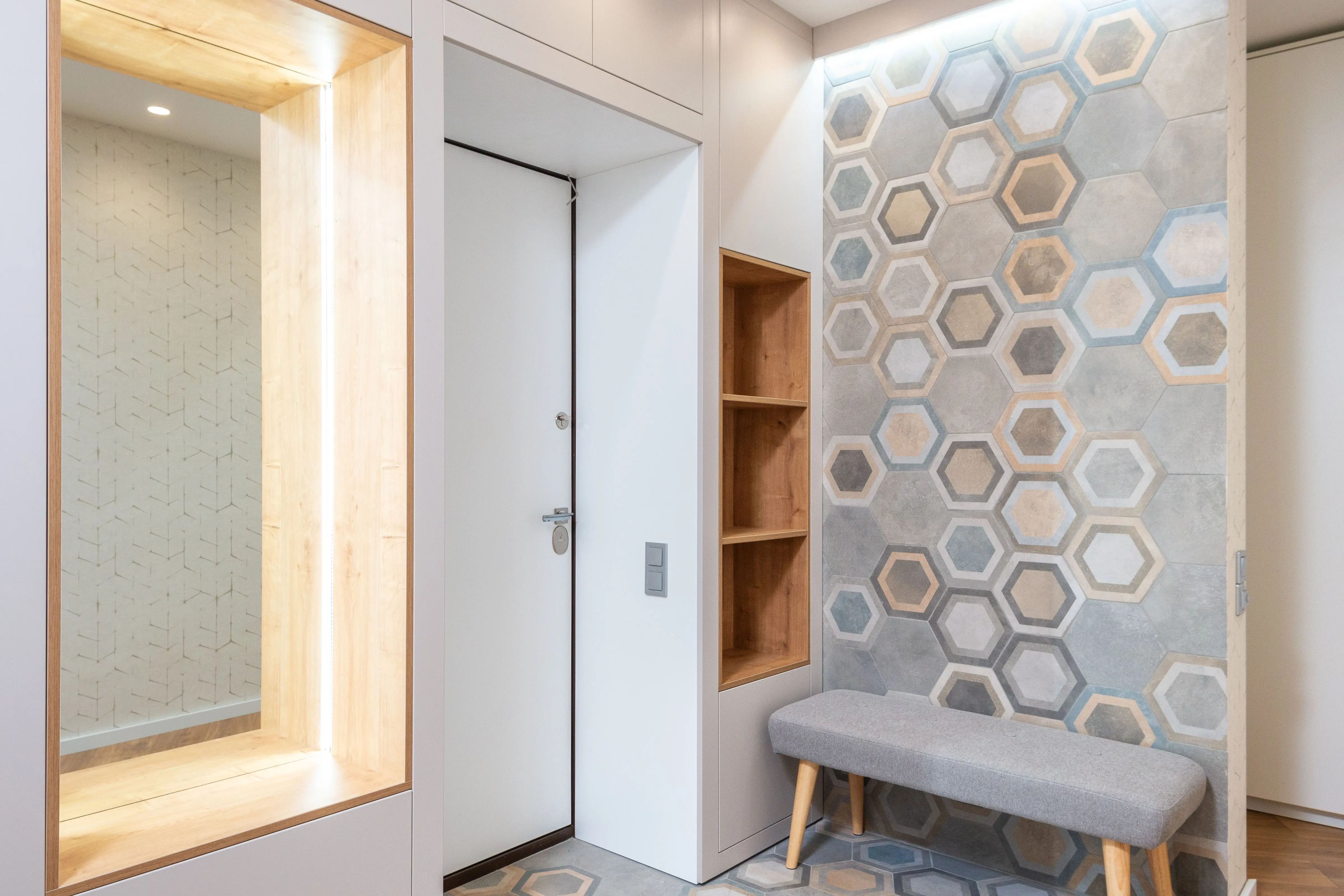 decorative tile Lobby interior with entrance door and wall with hexagonal ornament against fabric bench and mirror with shiny light at home
