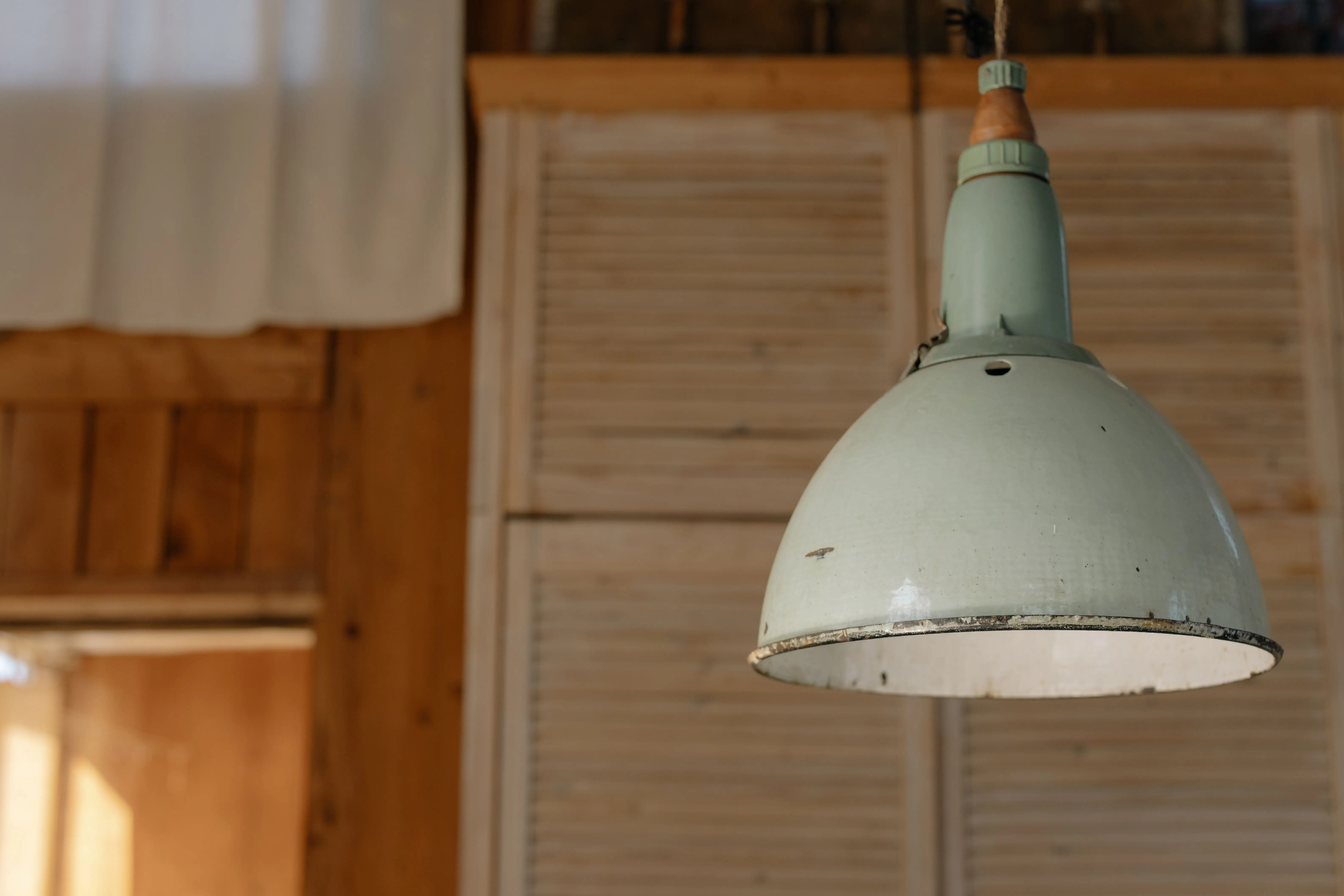 farmhouse light fixture A vintage industrial ceiling lamp hanging in a rustic room with wooden elements.
