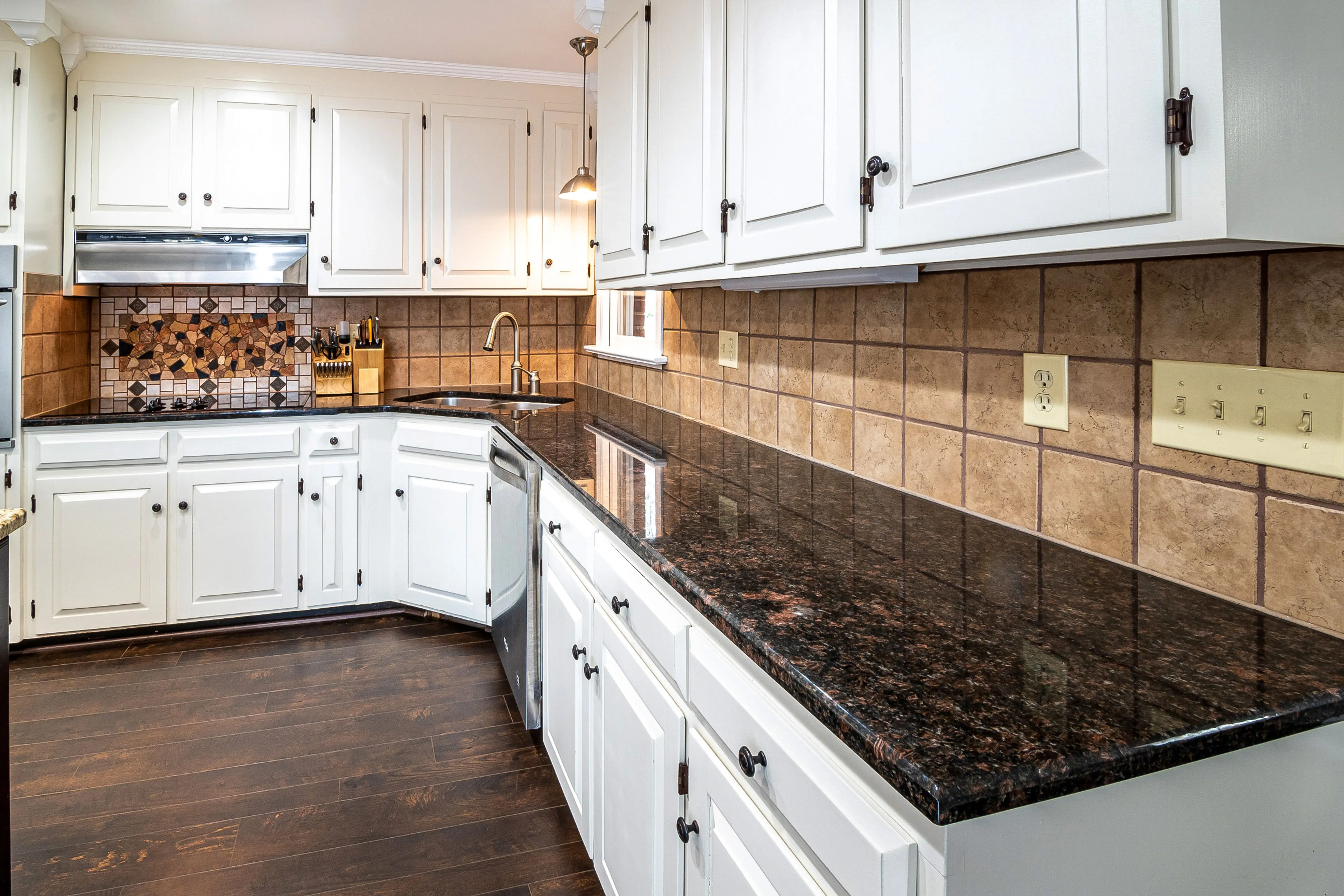 gray granite countertops Stylish kitchen featuring granite countertops, white cabinets, and a tiled backsplash, perfect for a contemporary home.