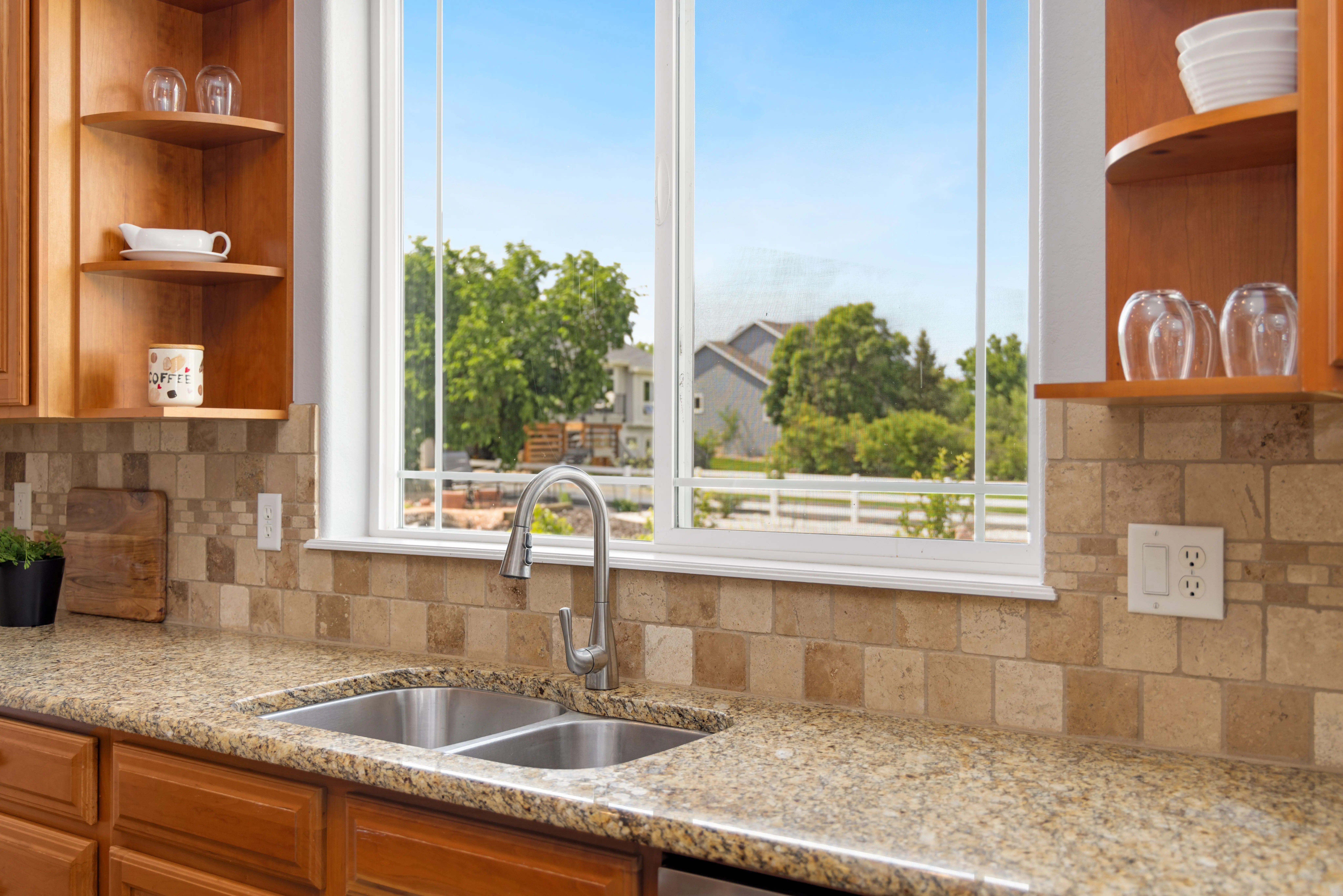 cinnamon slate Elegant kitchen featuring wooden cabinets, granite countertops, and a scenic view through a large window.