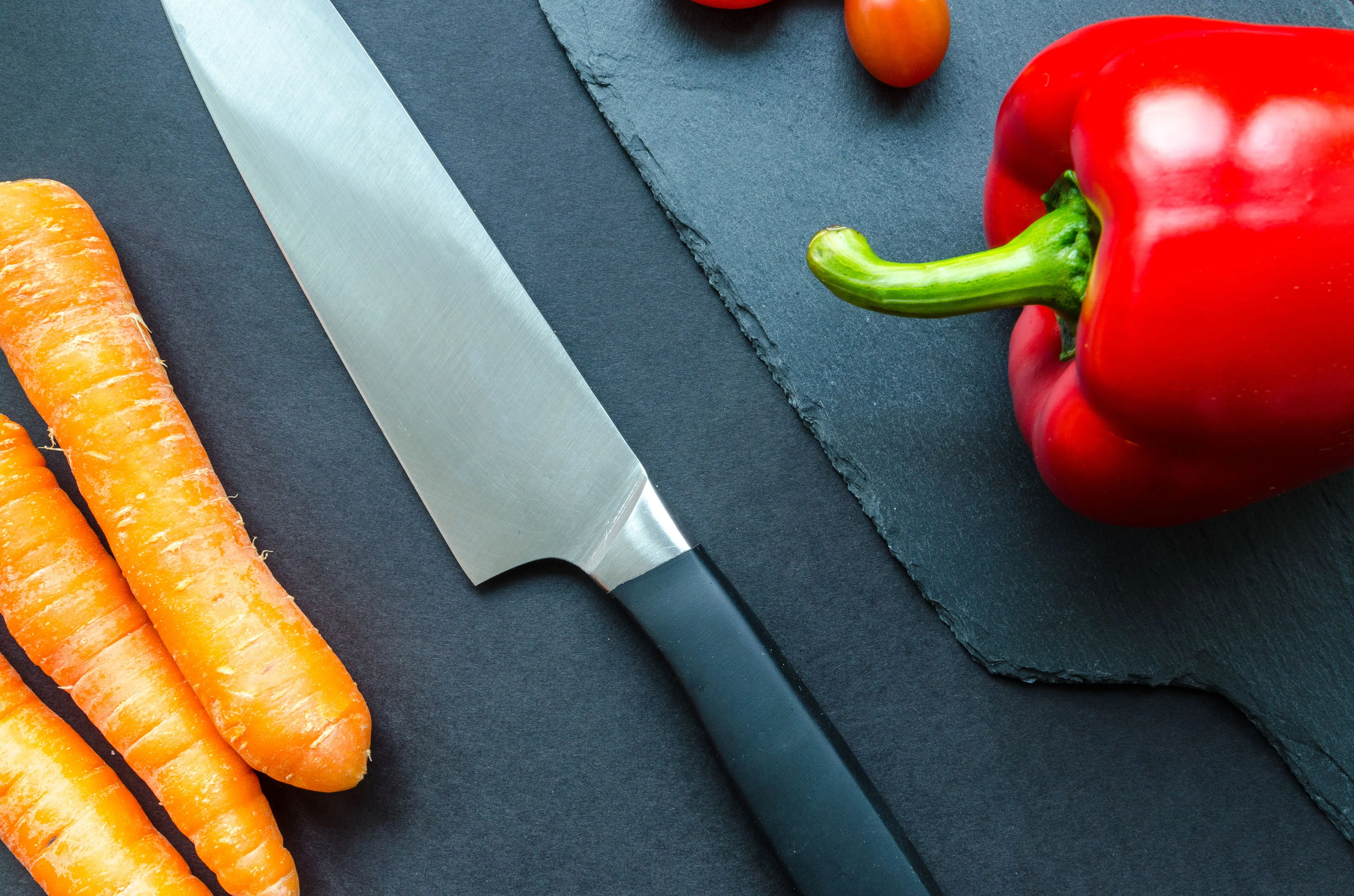 cinnamon slate color Top view of fresh carrots, red pepper, and tomatoes with a knife on a slate board.
