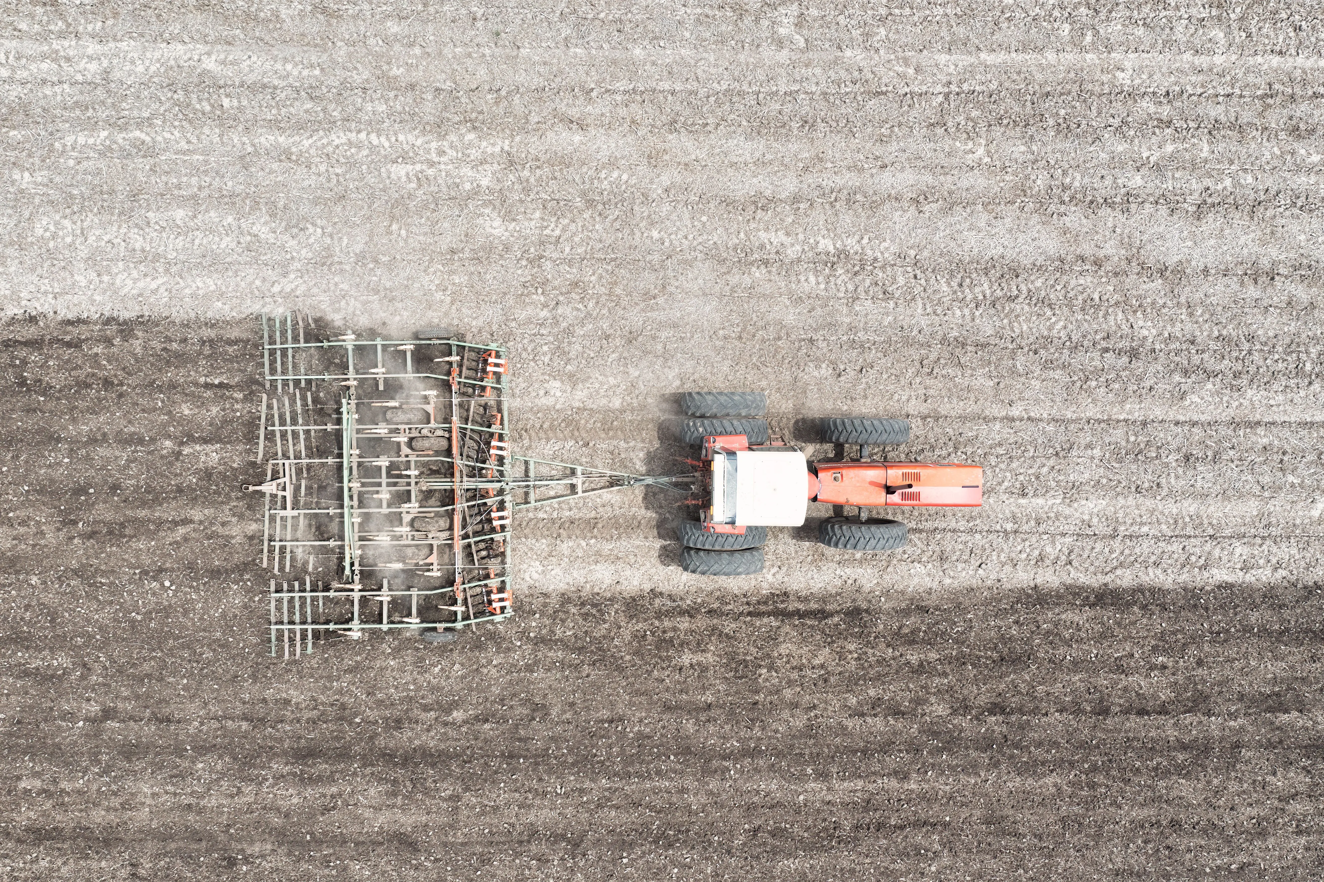 grass seed for sun and shade Top view of a tractor plowing agricultural land in Minnesota, showcasing farming machinery in action.