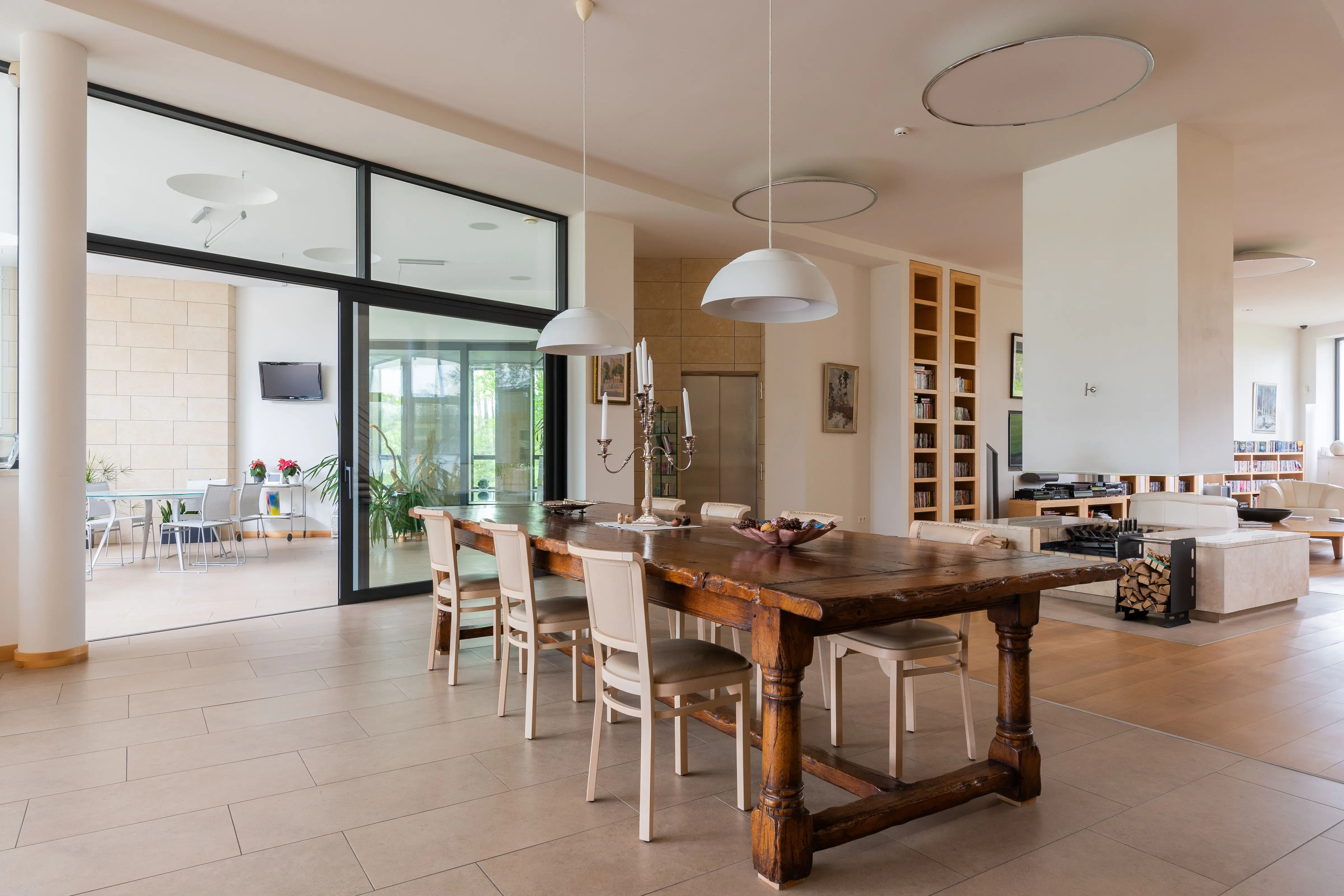 extension dining table Wooden table with candlestick and chairs placed near modern living room in stylish apartment with hanging lamps against doorway overlooking terrace