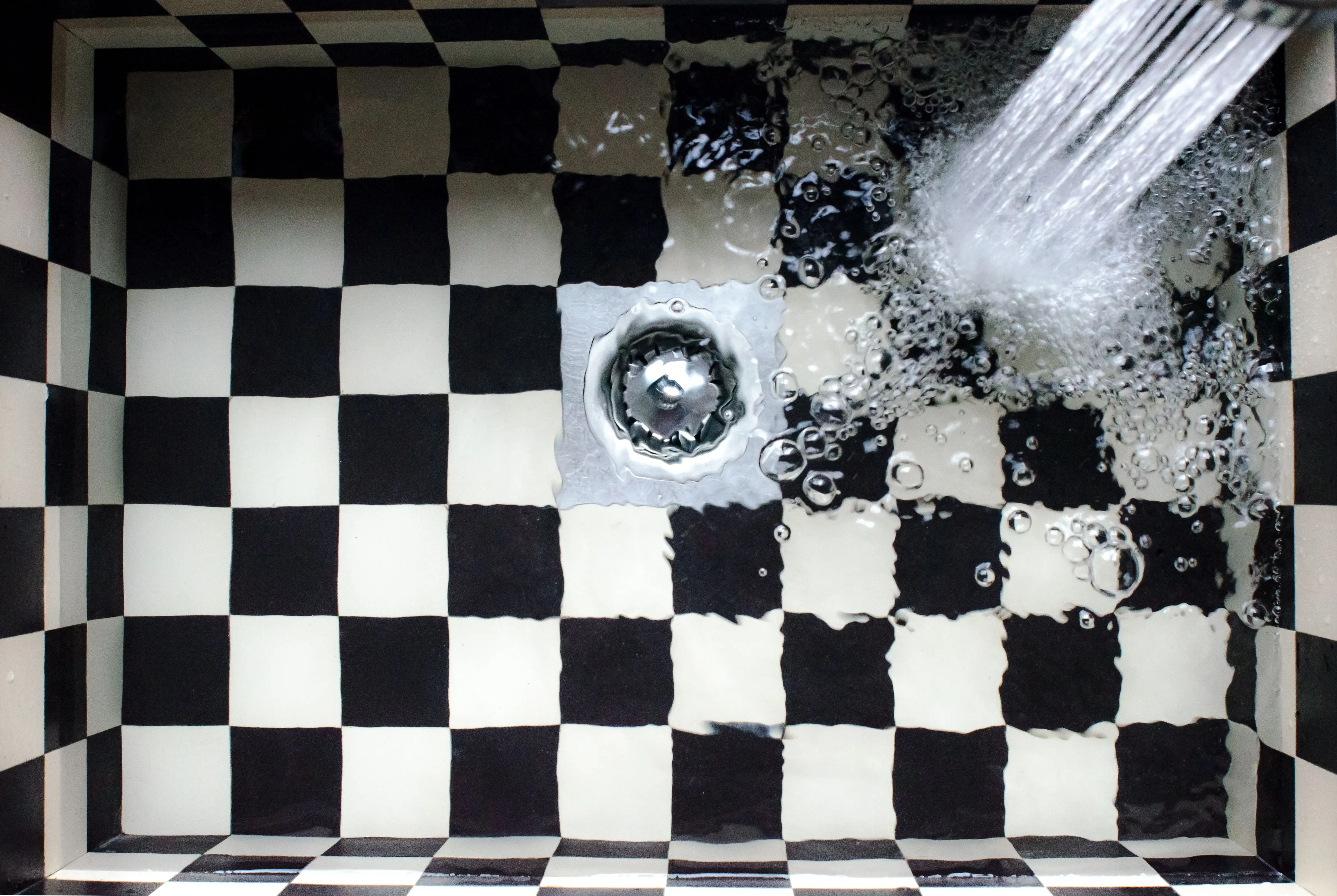 bathroom sink parts Top view of a checkered sink with water splashing, showcasing elegant design.